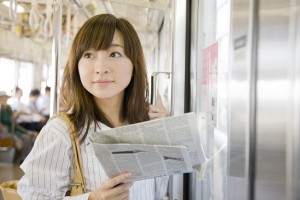 電車の中で新聞を読む女性